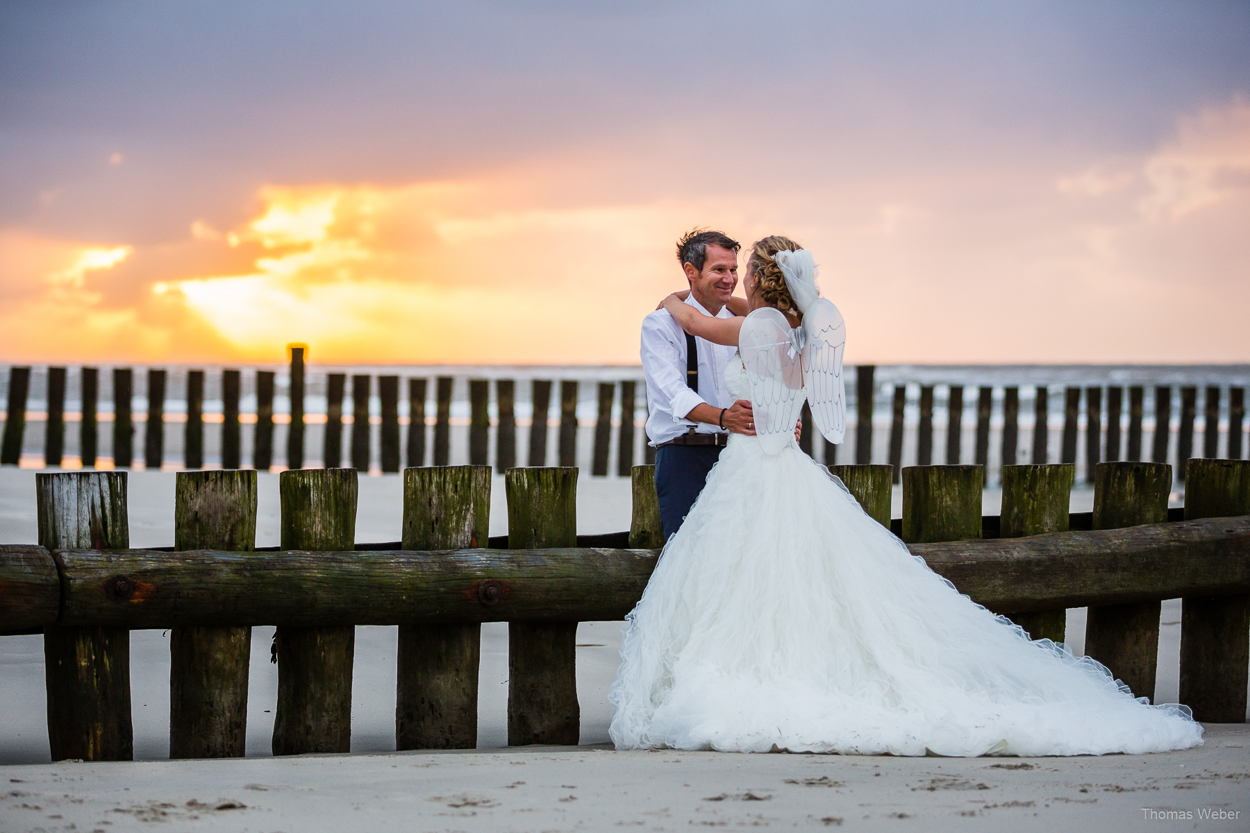 Hochzeitsfotograf auf Wangerooge, moderne Hochzeitsfotos mit Hochzeitskleid am Strand bei Sonnenuntergang, Hochzeitsfotograf Thomas Weber aus Oldenburg